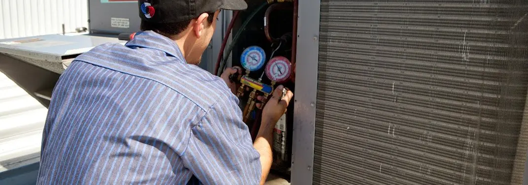 HVAC technician servicing a condenser unit in Gallatin